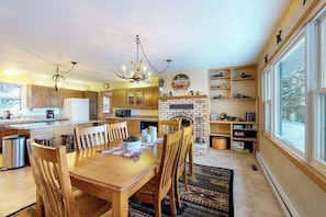 A spacious kitchen with wooden cabinets, a dining table, and a fireplace. - Lakefront, dog-friendly home with beach access, kayaks and firepit (Phelps)
