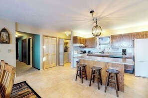 A modern kitchen with a central island, wooden cabinets, and a chandelier. - Lakefront, dog-friendly home with beach access, kayaks and firepit (Phelps)