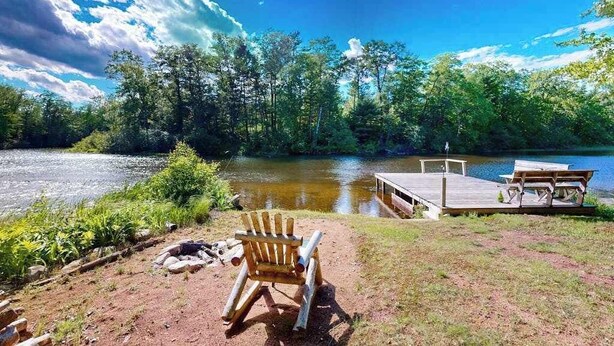 Un camping frente al lago con muelle, mesa de picnic y silla de madera.