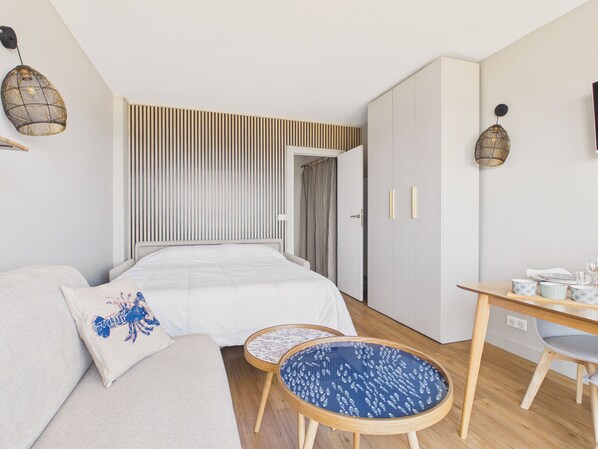 A bedroom with a bed, a sofa, a small table, a wardrobe, and a desk with a chair. - Apartment with sea view 100m from the beach (Le Croisic)