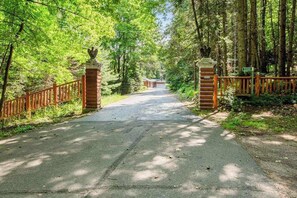 A paved pathway leading to a gated entrance with a wooden fence and a stone pillar. - Dog-friendly and secluded lakefront gem with a full bar, private dock, and views (Phelps)