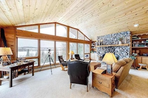 A cozy living room with a large window, wooden ceiling, and a stone wall. - Dog-friendly and secluded lakefront gem with a full bar, private dock, and views (Phelps)