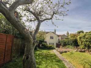 A residential property with a garden, a pathway, and a house with a visible chimney. - September Cottage (Weymouth)