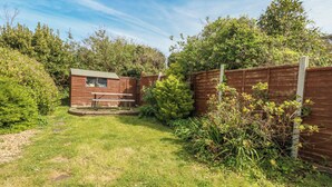 A backyard with a wooden shed, a picnic table, and a wooden fence. - September Cottage (Weymouth)