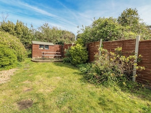 A backyard with a wooden shed, a picnic table, and a wooden fence. - September Cottage (Weymouth)