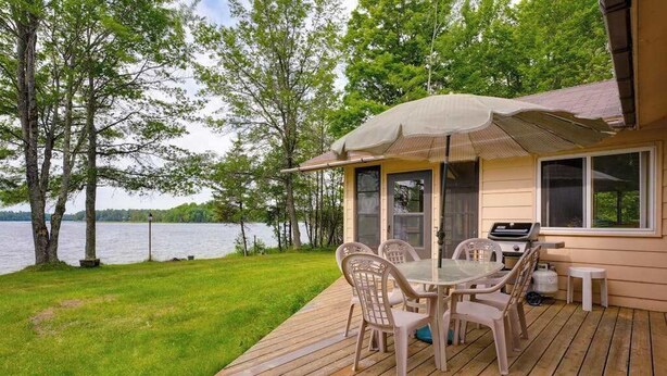 A deck with a table and chairs, a grill, and a view of a lake. - Lakefront haven with three living areas and WiFi (Manitowish Waters)