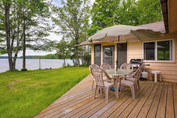 A deck with a table and chairs, a grill, and a view of a lake. - Lakefront haven with three living areas and WiFi (Manitowish Waters)