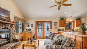 A living room with a sofa, coffee table, fireplace, and a view through a glass door. - Lakefront haven with three living areas and WiFi (Manitowish Waters)