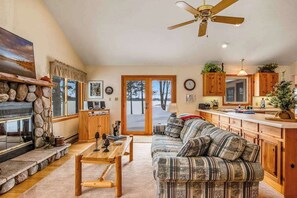 A living room with a sofa, coffee table, fireplace, and a view through a glass door. - Lakefront haven with three living areas and WiFi (Manitowish Waters)
