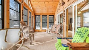 A cabin interior with large windows, wooden walls, and multiple Adirondack chairs. - Lakefront haven with three living areas and WiFi (Manitowish Waters)