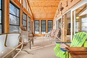 A cabin interior with large windows, wooden walls, and multiple Adirondack chairs. - Lakefront haven with three living areas and WiFi (Manitowish Waters)