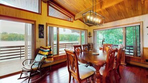 Un comedor con una mesa y sillas de madera, ventanas amplias y vistas a zonas verdes.