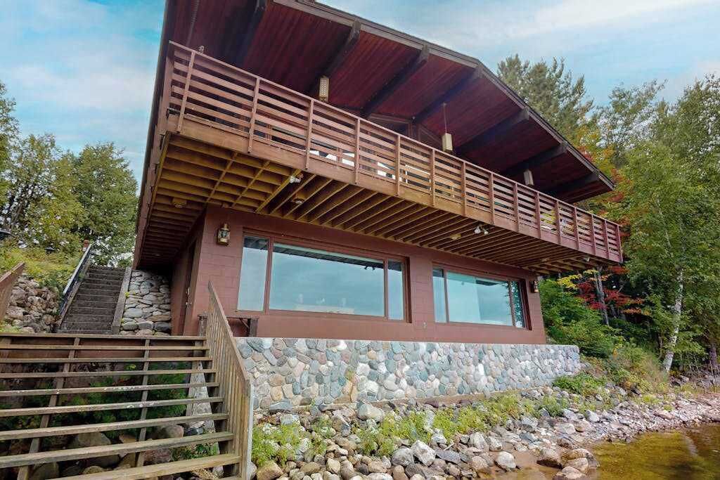 Un bâtiment moderne à deux étages, doté de fondations en pierre, de grandes fenêtres et d’un balcon en bois.