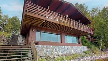 Un bâtiment moderne à deux étages, doté de fondations en pierre, de grandes fenêtres et d’un balcon en bois.