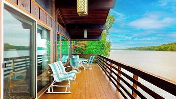 Une terrasse en bois avec des sièges extérieurs et une vue sur une étendue d’eau.