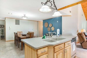 A kitchen with a granite countertop, wooden cabinets, a built-in dishwasher, and a dining area with a table and chairs.