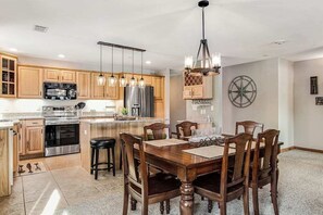 A modern kitchen with wooden cabinets, stainless steel appliances, and a dining area with a wooden table and chairs. - Condo at waterfront resort with golf course views, central AC, W/D, & pool (Arkdale)