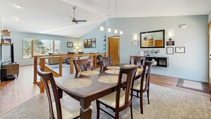 A dining area with a wooden table, chairs, and a ceiling fan. - Green side smart home with golf, beach/lake access, off-site dock & EV charger (Nekoosa)