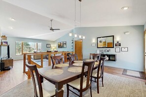 A dining area with a wooden table, chairs, and a ceiling fan. - Green side smart home with golf, beach/lake access, off-site dock & EV charger (Nekoosa)