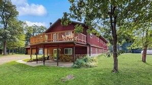A two-story wooden house with a balcony, a covered porch, and a well-maintained lawn. - Cozy wooded duplex w/ WiFi, full kitchen, shared W/D & near lakes & trails (Arkdale)