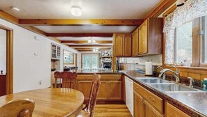 A kitchen with wooden cabinets, a granite countertop, and a dining area with a wooden table and chairs. - Cozy wooded duplex w/ WiFi, full kitchen, shared W/D & near lakes & trails (Arkdale)