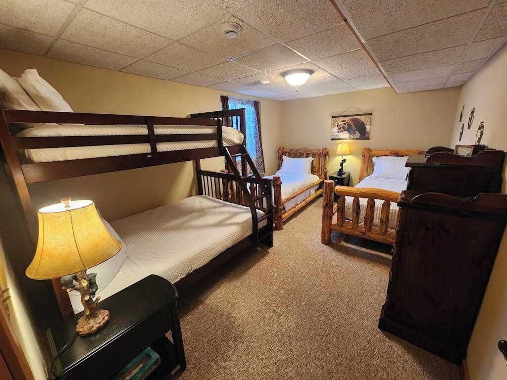 A room with bunk beds, a desk, a lamp, and a dresser.