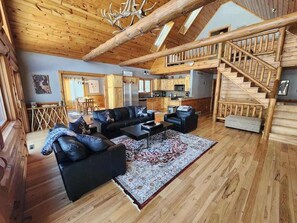 L’intérieur d’une cabane en rondins comprenant un salon, une cuisine et un escalier.