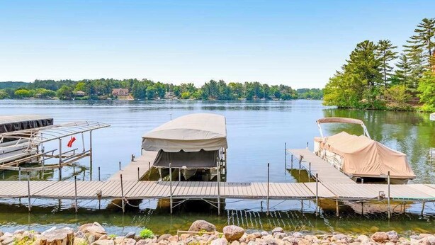 A calm lake with docked boats and a tent on a wooden pier. - Waterfront condo with resort amenities, grill, firepit, jetted tub, & partial AC (Wisconsin Dells)