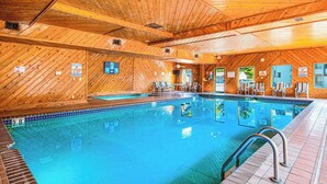 An indoor swimming pool with wooden walls and ceiling, surrounded by lounge chairs. - Waterfront condo with resort amenities, grill, firepit, jetted tub, & partial AC (Wisconsin Dells)
