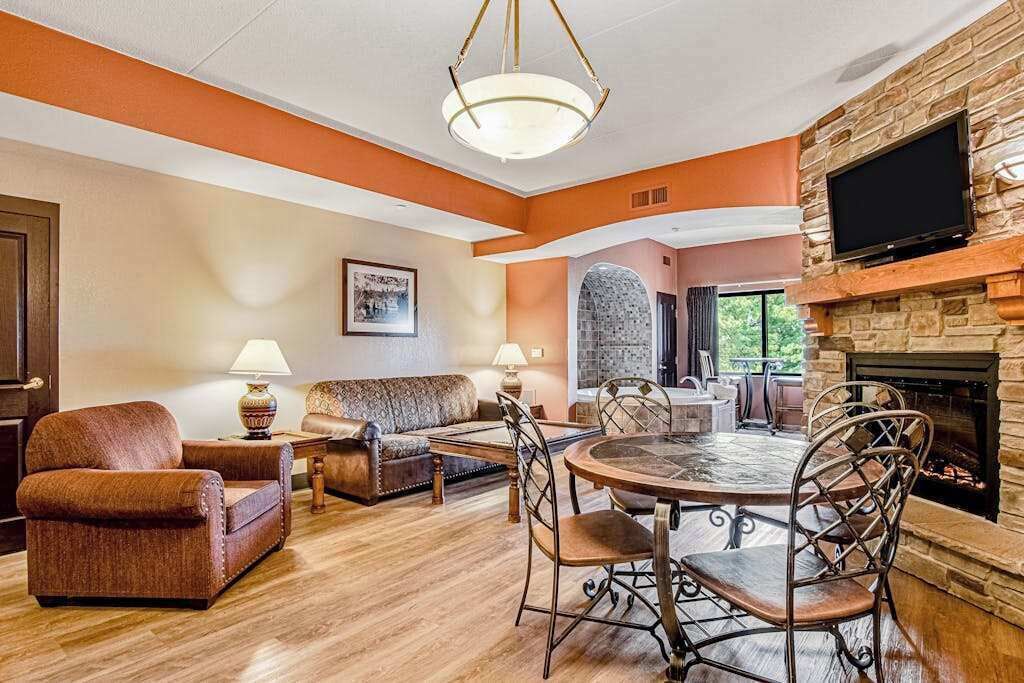 A living room with a fireplace, a dining table with chairs, a sofa, and a television mounted on the wall.