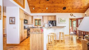 A spacious kitchen with wooden cabinets, a central island, and a dining area with wooden chairs.