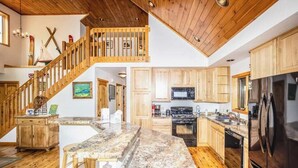A spacious kitchen with wooden cabinets, a granite countertop, and a stainless steel refrigerator.