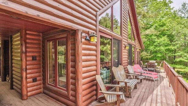 A log cabin with a deck, sliding glass doors, and outdoor seating.