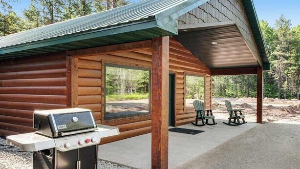 A log cabin with a grill, two Adirondack chairs, and a covered patio. - Modern dog-friendly cabin with hot tub, gas fireplace, patio, grill, & AC (Conover)