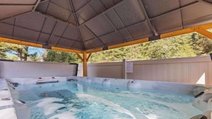 A hot tub area with a covered roof, wooden deck, and a white fence. - Modern dog-friendly cabin with hot tub, gas fireplace, patio, grill, & AC (Conover)