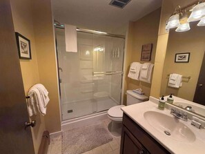 Ein Badezimmer mit einer Duschkabine, Toilette, Waschbecken mit Spiegel und Handtuchhalter.