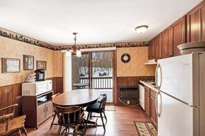 Eine Küche mit Holzausstattung, einem Esstisch, Stühlen, einem Kühlschrank und einem Kamin.