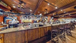 Un espace bar avec un plafond en bois, des tabourets de bar et un comptoir où sont disposés des verres et des bouteilles.