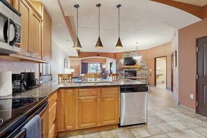 Una cocina con armarios de madera, lavavajillas, estufa y luces colgantes.