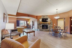 Una sala de estar con chimenea, mesa de billar y comedor con sillas de metal.
