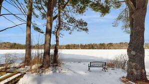 Een bank in een besneeuwd landschap met bomen en een helder uitzicht op de horizon.