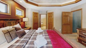 Een hotelkamer met een bed, nachtkastje, lamp, plafondventilator en houten deuren.