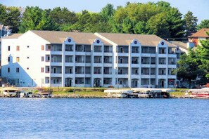 A multi-story hotel with balconies, located near a body of water with boats docked. - Waterfront condo with shared pools, hot tubs, beach, lake access, WiFi &  A/C (Wisconsin Dells)