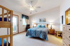 A bedroom with a bed, a ceiling fan, a dresser, and a window with curtains. - Waterfront condo with shared pools, hot tubs, beach, lake access, WiFi &  A/C (Wisconsin Dells)