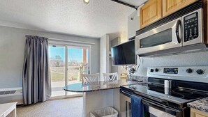 A kitchen with a microwave, oven, and a small island with a chair.