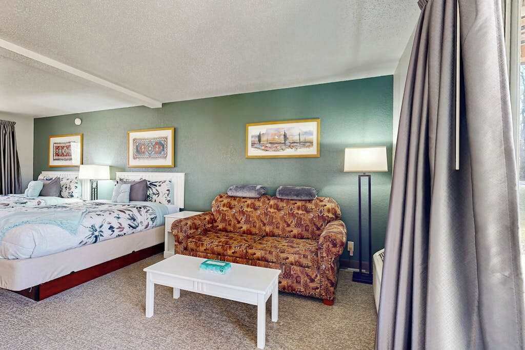 Une chambre d’hôtel comprenant un lit, un canapé, une table basse et deux lampes fixées au mur.