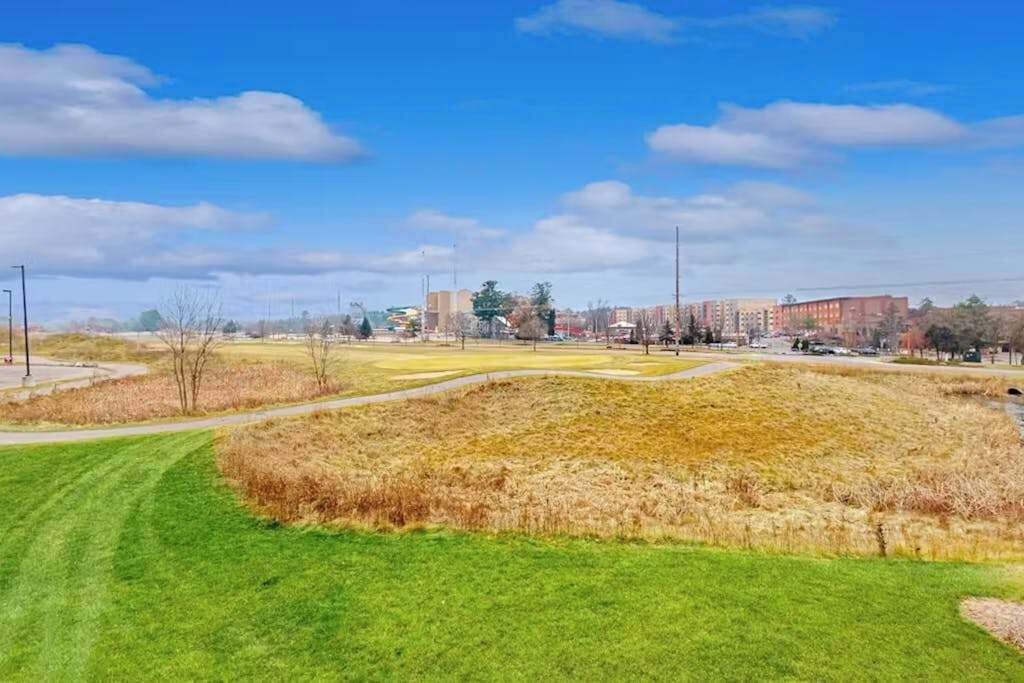 A golf course with a green fairway, a sand bunker, and a water hazard.