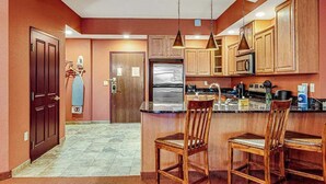 Una cocina con armarios de madera, un refrigerador, un microondas y una barra con sillas.