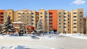 Ein mehrstöckiges Hotel mit einer Steinfassade, Balkonen und einem Parkplatz.
