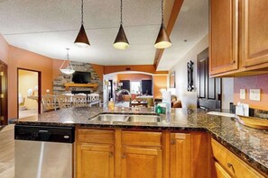 A kitchen with granite countertops, wooden cabinets, a dishwasher, and pendant lighting. - Dells Resort Retreat w/ Adventure Included (Wisconsin Dells)